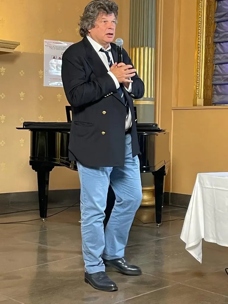 Jean-Marie Legé parle au micro devant un piano, au Colloque international sur la voix, à Paris, en 2022